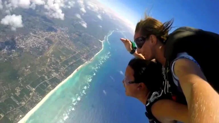 A tandem skydiving pair in freefall look out over the Kenyan coast, the reef and Indian Ocean stretching below them